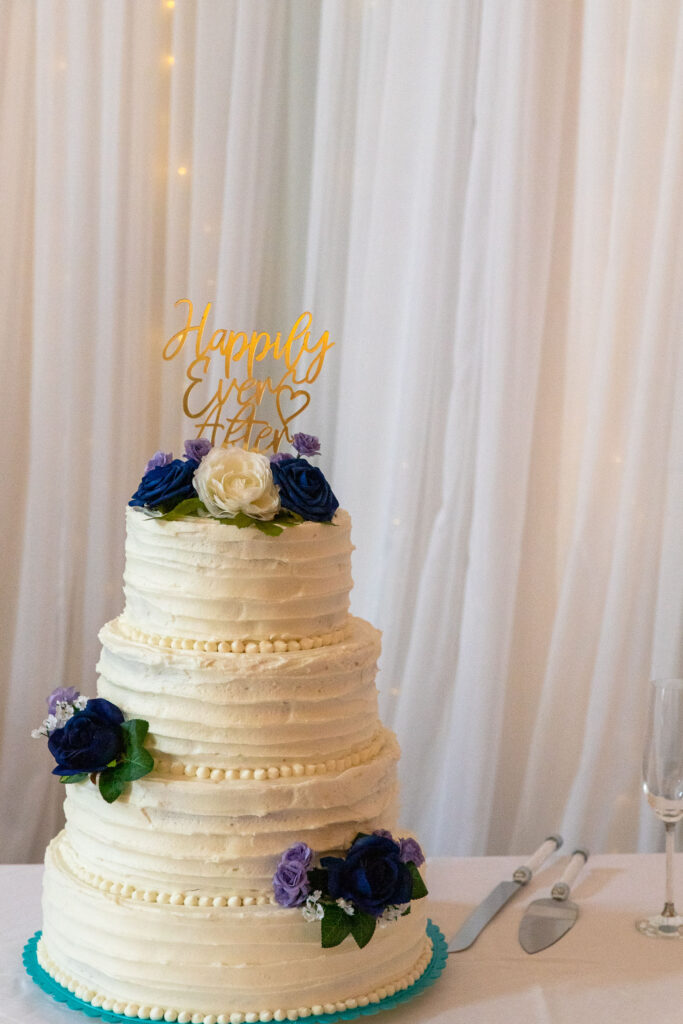 white wedding cake with blue, purple and white flowers