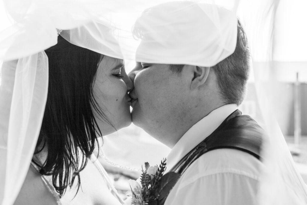 black and white photo of bride and groom kissing