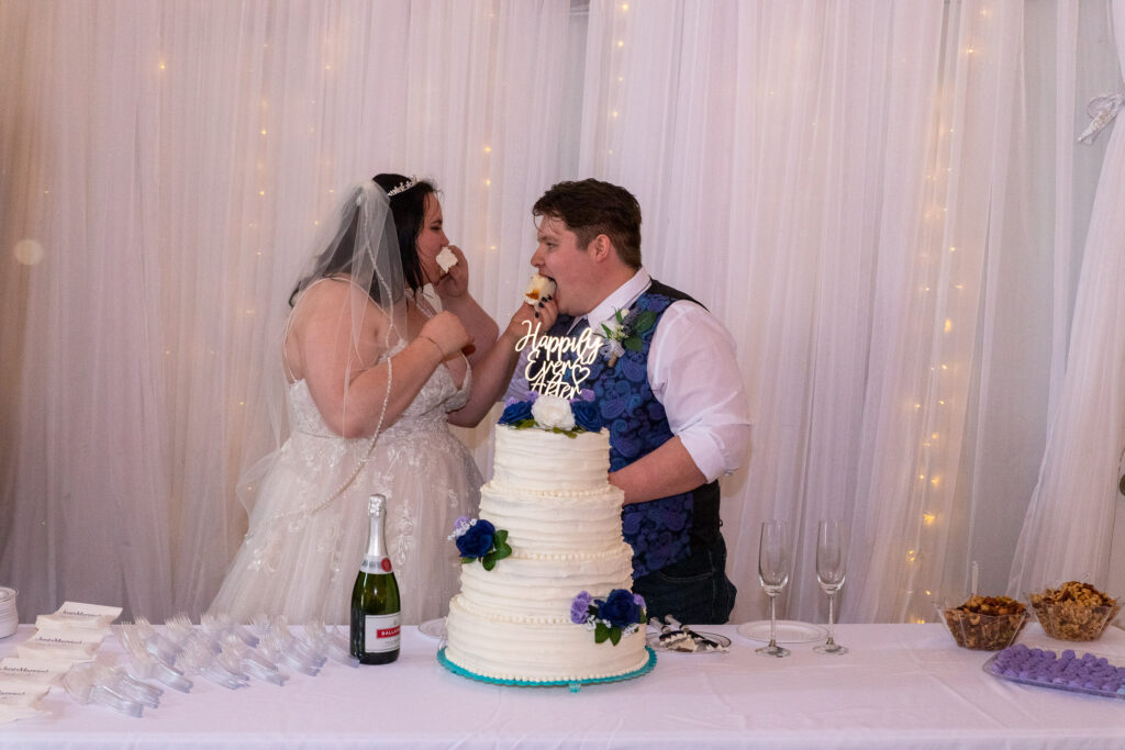 bride and groom with wedding cake at lakeside wedding venue