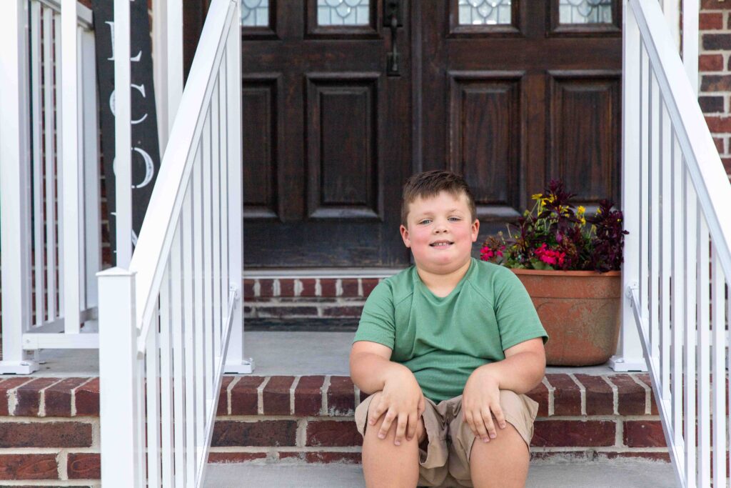 little boy sitting on porch steps